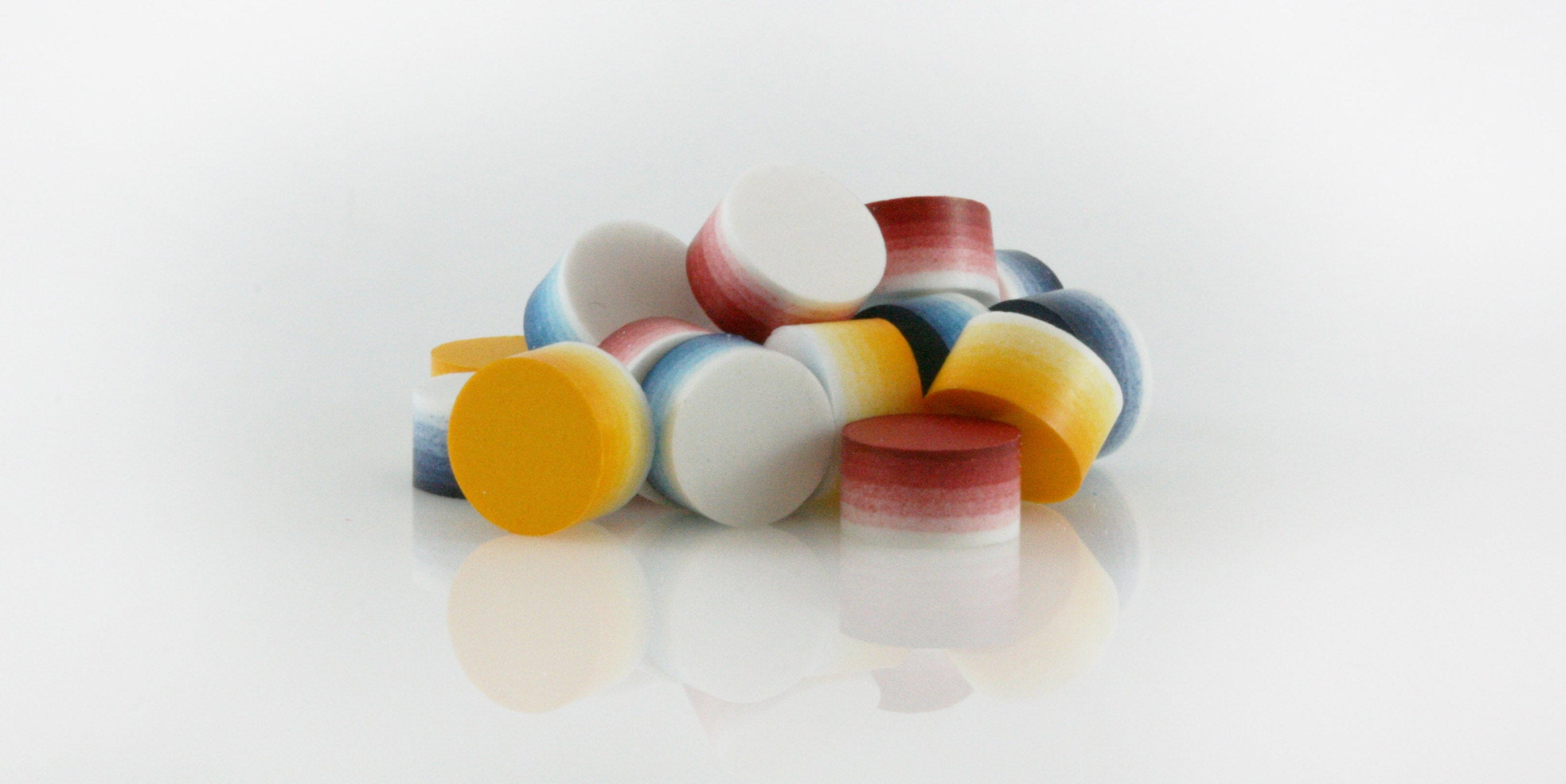 Pile of layered colored tablet pills on a white background-Supplement-Nutraceutical