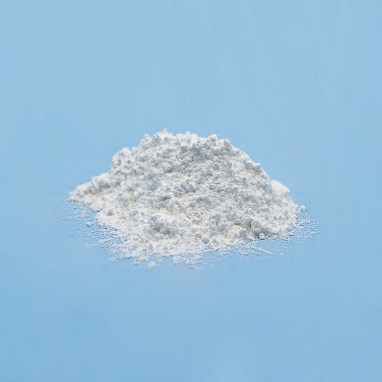 Sodium Stearyl Fumarate-Pile of white Sodium Stearyl Fumarate Powder on light blue background-Excipient-Granules