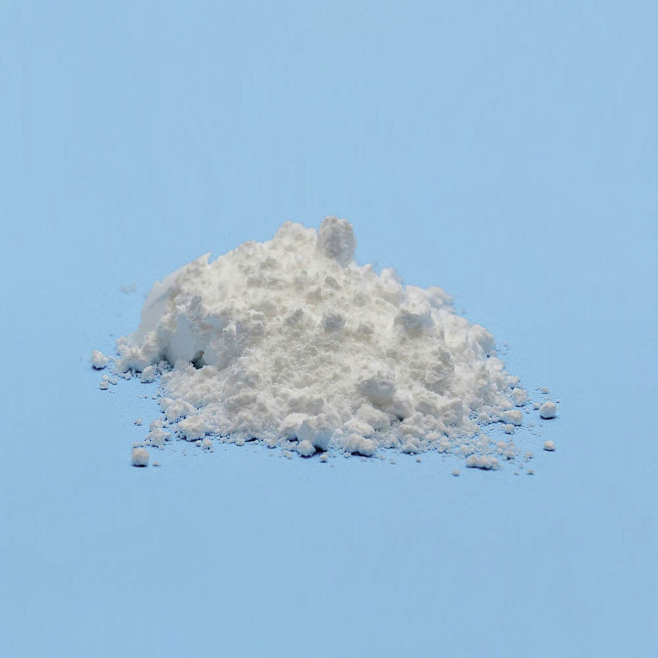 Magnesium Stearate-Pile of white Magnesium Stearate Powder on light blue background-Excipient-Granules