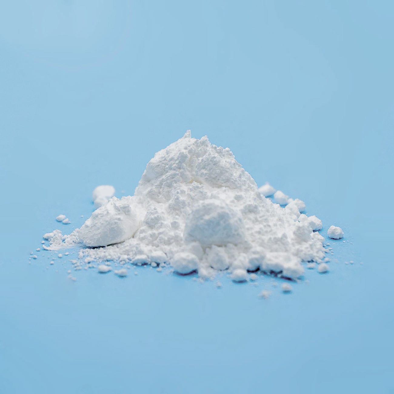 Silicon Dioxide-Silica-Sio2-Pile of white Silica Powder on light blue background-Excipient-Granules